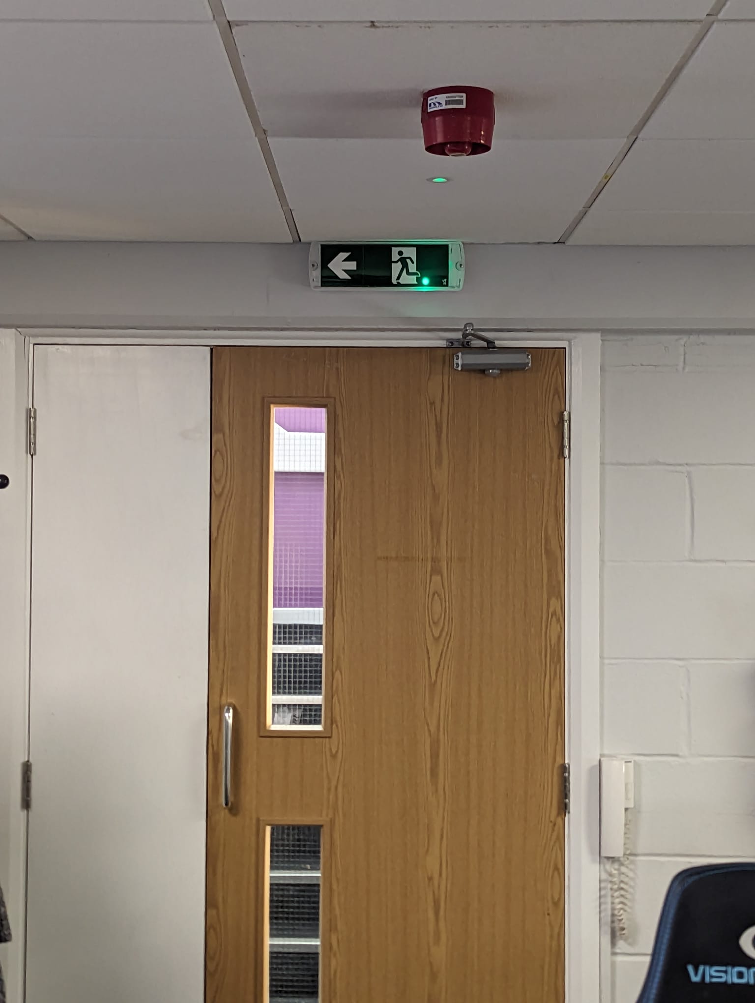 Completed timber commercial fire door beneath an emergency exit sign