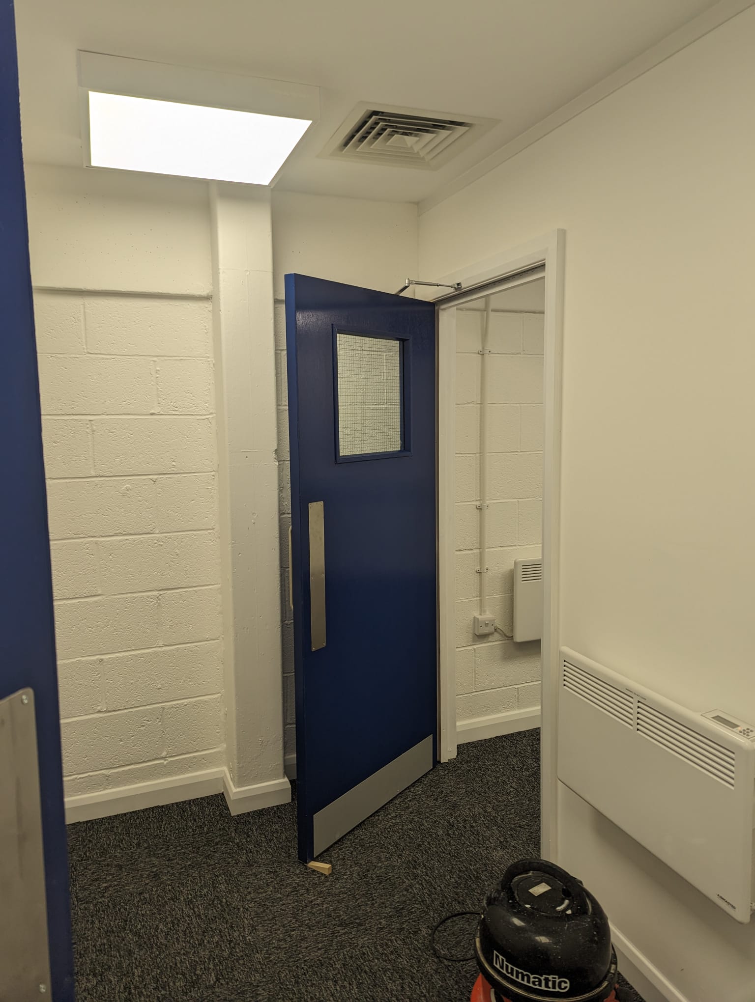 Completed blue commercial fire door with vision panel and closer